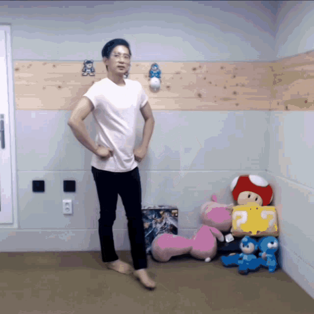 a man in a pink shirt is standing in a room with stuffed toys