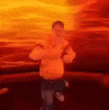 a blurry picture of a man in an orange shirt standing in front of a red background .