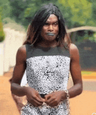 a man dressed as a woman in a leopard print dress is walking down the street .