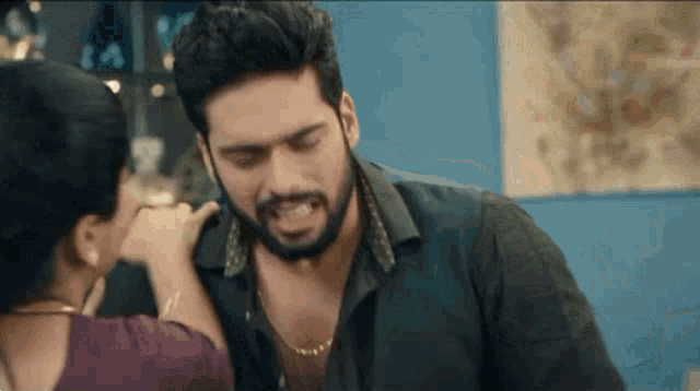 a man with a beard is being touched by a woman in a room .
