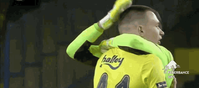 a man in a yellow shirt with the word halley on the back is hugging another man