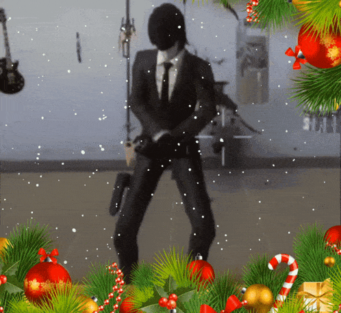 a man in a suit stands in front of a christmas tree