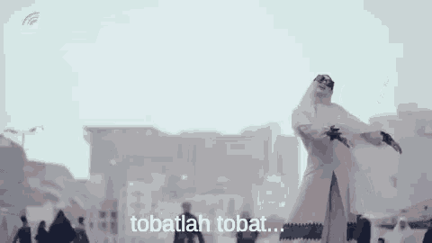 a woman in a hijab is standing in front of a crowd of people in a city .