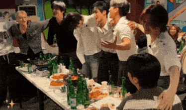 a group of people are standing around a table with bottles of water