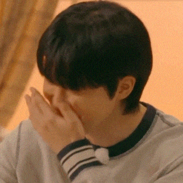 a close up of a person covering their mouth with their hands .
