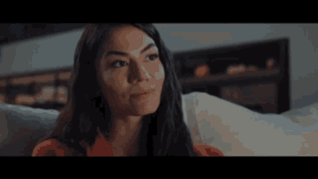 a woman in a red shirt is sitting on a couch with her eyes closed