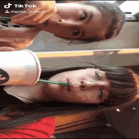 two girls drinking from a starbucks cup with a green straw ..