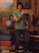 a man in a green shirt is standing in a room with a globe on the wall .