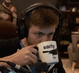 a man wearing headphones is drinking from an early coffee mug