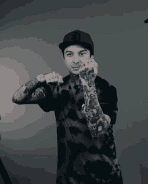 a man with tattoos on his arms is wearing a hat with the letter j on it