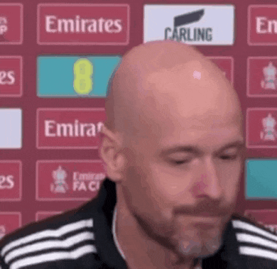 a bald man with a beard is wearing a black and white adidas shirt and making a funny face .