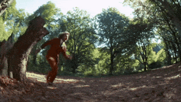 a person in an orange jumpsuit is running through the woods