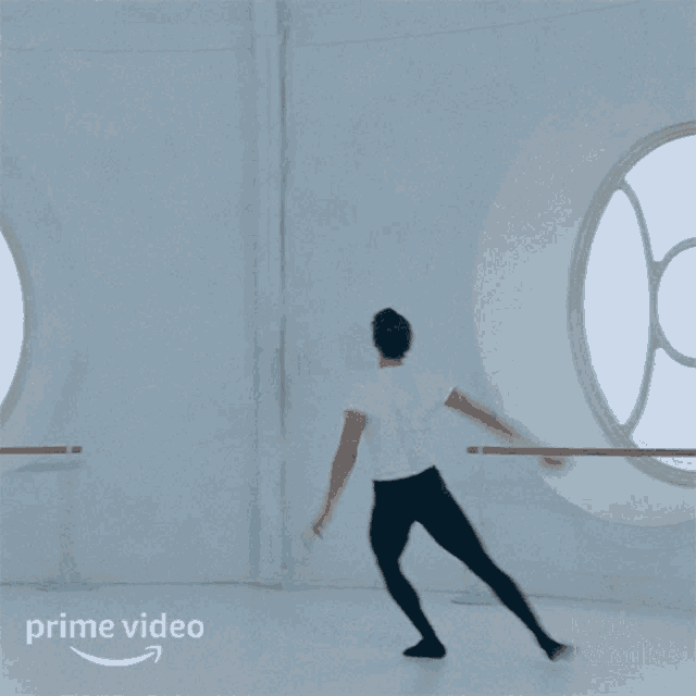 a man in a white shirt and black pants is dancing in front of a window with the word prime video on the bottom right