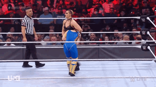 a woman in a wrestling ring with a referee in the background