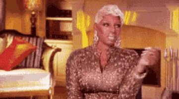 a woman in a gold dress is sitting in a living room holding a cup .