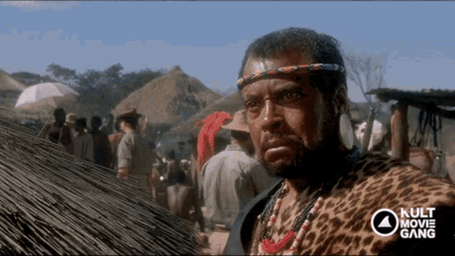 a man wearing a leopard print headband stands in front of a crowd of people with the words kult movie gang on the bottom