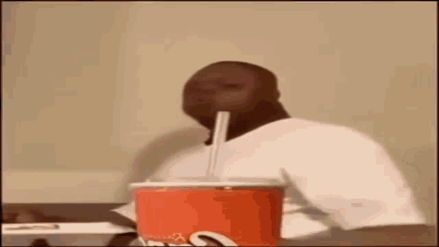 a man is drinking a soda with a straw through his nose .