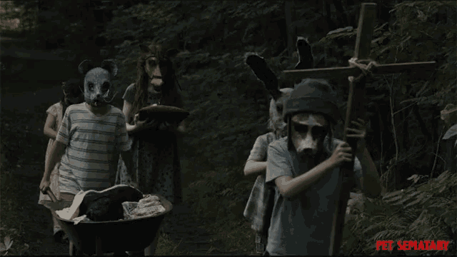 a group of children wearing animal masks carrying a wheelbarrow and a cross in a scene from pet sematary