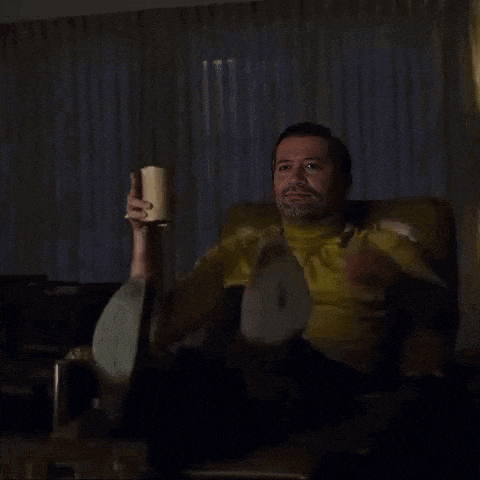 a man is sitting in a chair holding a cup and pointing .