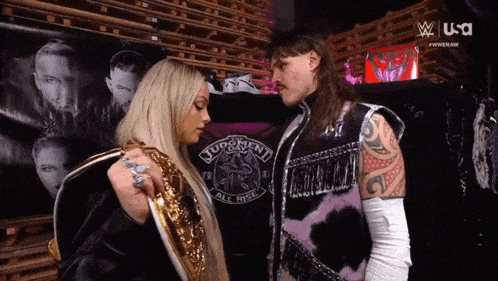 a man and a woman are standing next to each other and the man is wearing a vest that says turonent all rise