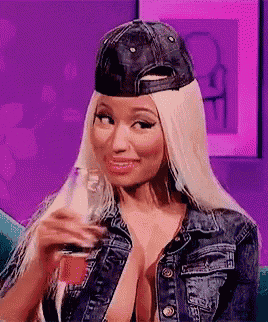 a woman wearing a denim jacket and a baseball cap is holding a glass of soda .