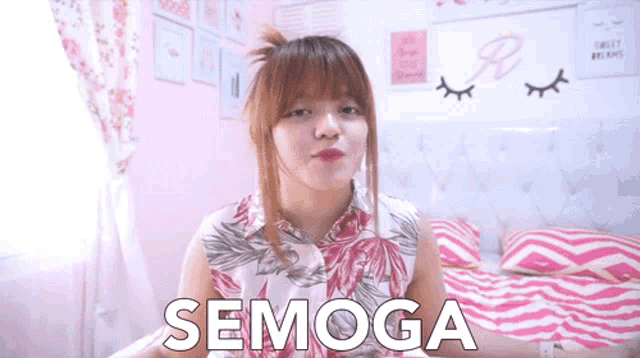 a woman is sitting on a bed with the word semoga written on her chest