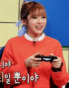 a girl in a red sweater is holding a video game controller and smiling