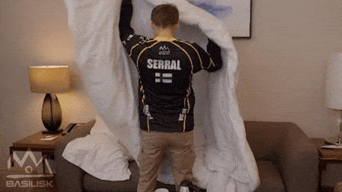 a man wearing a jersey that says serral is making a bed