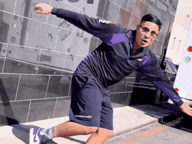 a man wearing a purple fedex jacket and shorts is dancing