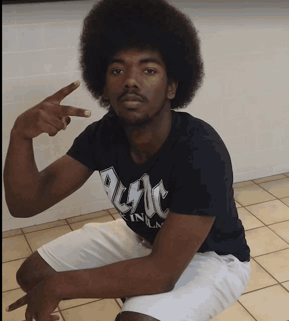 a man wearing a black ac dc shirt squats down