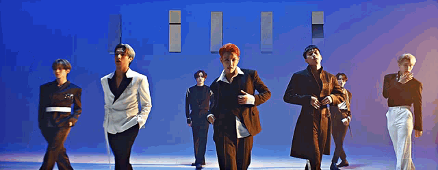 a group of men are dancing in front of a blue wall