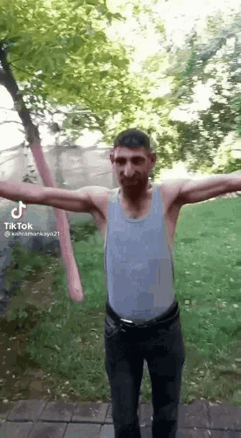 a man is standing with his arms outstretched in a park .