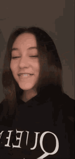 a young woman wearing a black hoodie is looking at the camera .