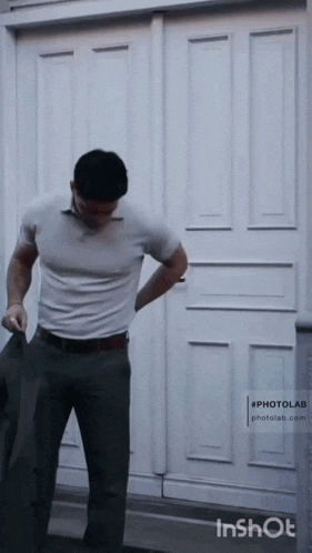 a man is standing in front of a white door with his hands in his pockets .