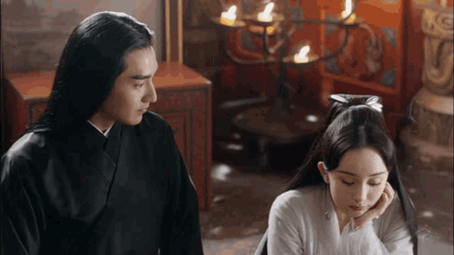 a man and woman are sitting next to each other in a room with candles .