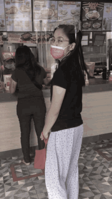 a woman wearing a mask is standing in front of a counter with a sign that says ' chicken ' on it