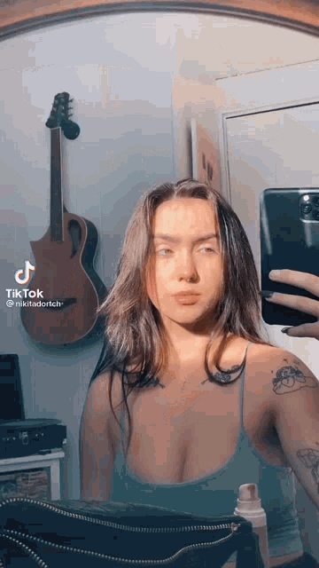 a woman is taking a selfie in front of a mirror with her phone .