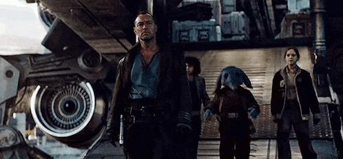 a group of people are standing next to each other in front of a large robot .