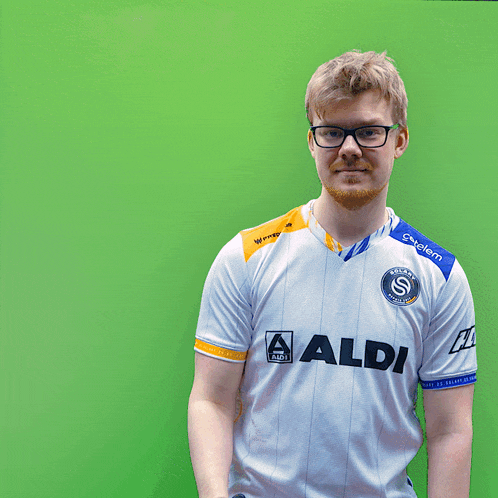 a man wearing an aldi shirt holds his finger to his lips
