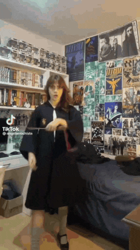 a girl in a harry potter costume is holding a wand in a room .
