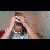 a person with dreadlocks is holding their head in their hands