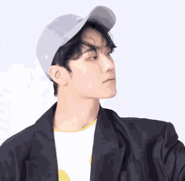 a man wearing a baseball cap and a black jacket looks to the side