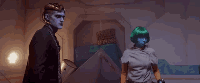 a man with blue paint on his face and a woman with green hair are standing next to each other in a room .