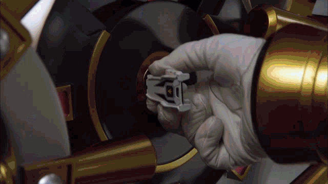 a hand in a white glove is holding a small object that says ' a ' on it