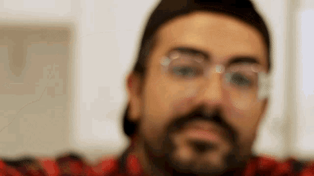a man with a beard and glasses is taking a selfie with his phone .