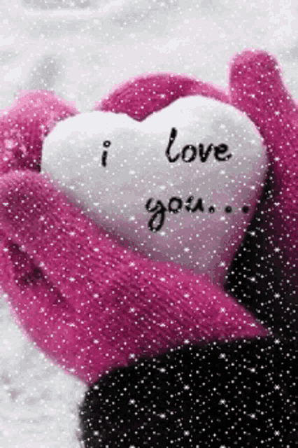 a person wearing pink mittens is holding a heart that says " i love you "