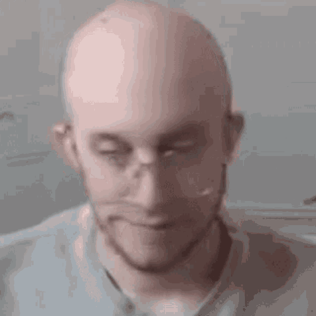 a bald man with a beard is wearing glasses and a microphone .