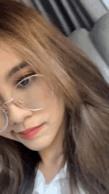 a woman wearing glasses and a white shirt is taking a selfie