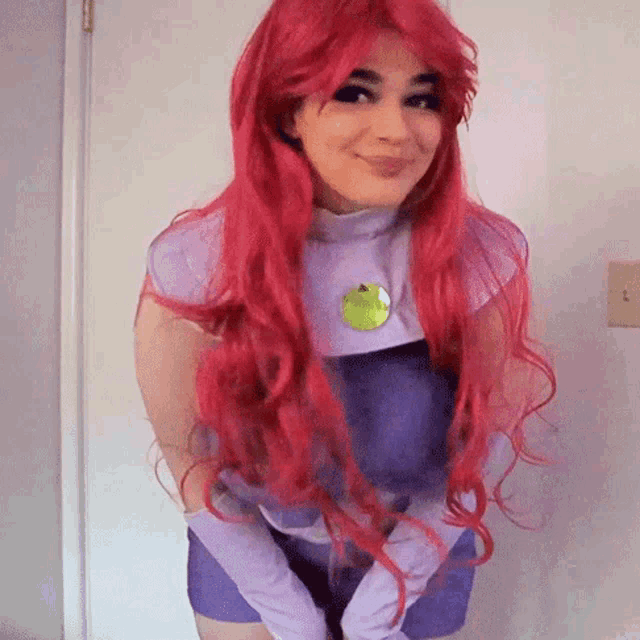 a woman with red hair is wearing a starfire costume and smiling