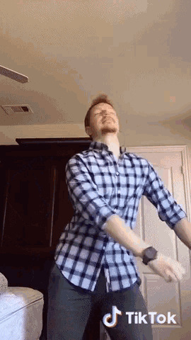a man in a plaid shirt is dancing in a room with a tiktok logo